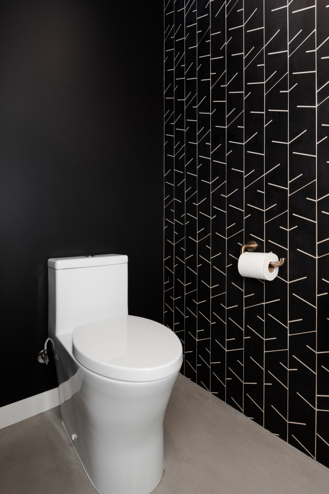 Exemple d'un petit WC et toilettes rétro en bois brun avec un placard sans porte, WC à poser, un carrelage noir, des carreaux de porcelaine, un mur noir, sol en béton ciré, une vasque, un sol gris et meuble-lavabo suspendu.