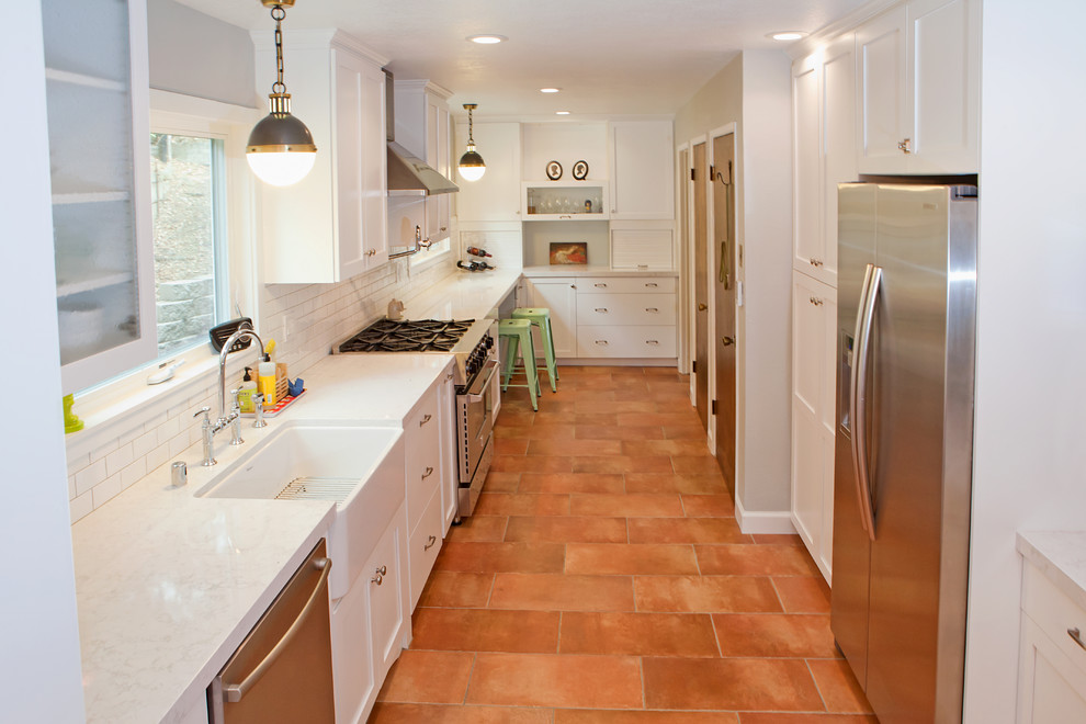 Mid-sized traditional galley separate kitchen in San Francisco with a farmhouse sink, shaker cabinets, white cabinets, quartz benchtops, white splashback, subway tile splashback, stainless steel appliances, terra-cotta floors and no island.