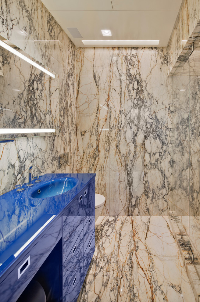Inspiration for a mid-sized contemporary 3/4 bathroom in New York with an integrated sink, flat-panel cabinets, blue cabinets, an alcove shower, beige tile, a two-piece toilet, marble, beige walls, marble floors, solid surface benchtops, beige floor, an open shower and blue benchtops.