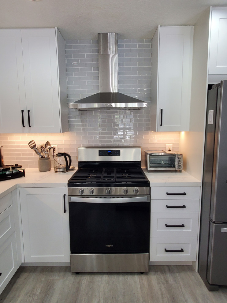 Idées déco pour une grande arrière-cuisine classique en L avec un placard à porte shaker, des portes de placard blanches, un plan de travail en quartz modifié et îlot.