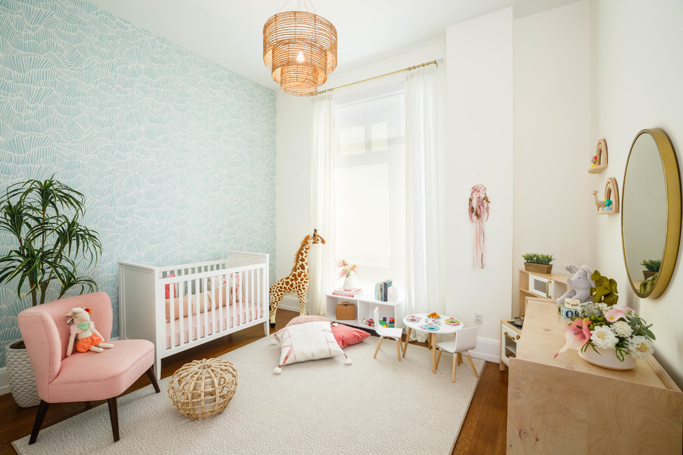 This is an example of a kids' room for girls in New York with white walls, medium hardwood floors and brown floor.