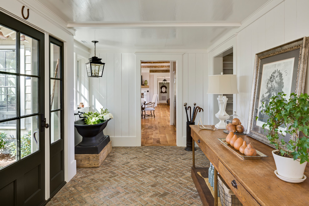 This is an example of a country foyer in Other with white walls, brick floors, a single front door and a glass front door.