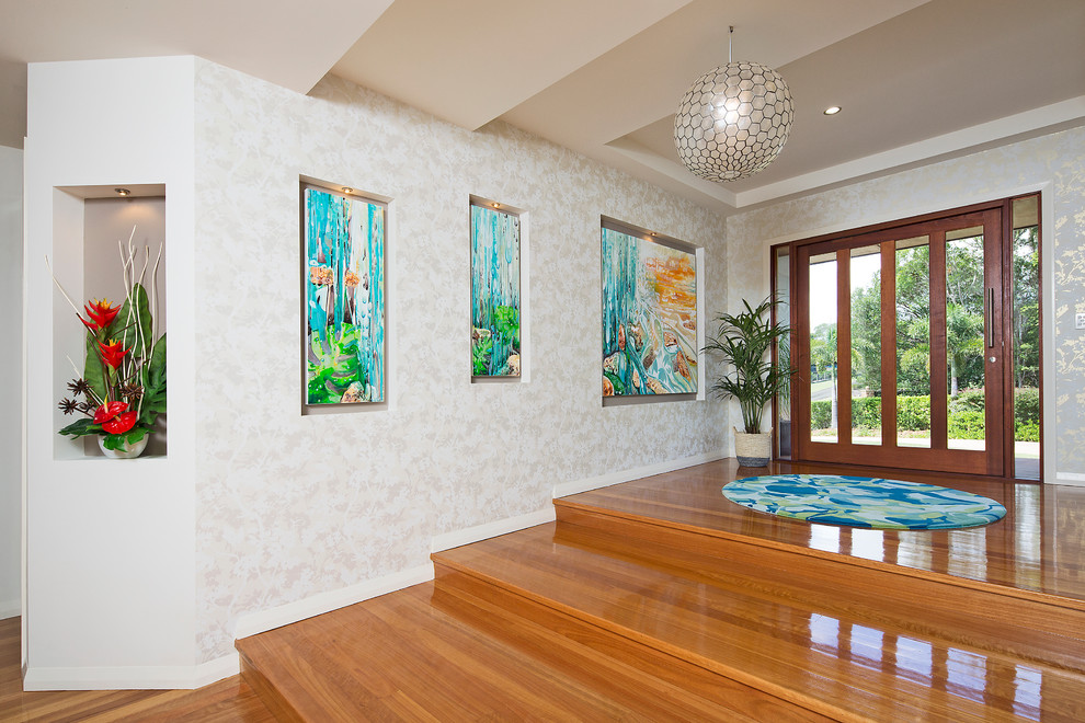 Design ideas for a large tropical foyer in Gold Coast - Tweed with white walls, medium hardwood floors, a pivot front door and a medium wood front door.
