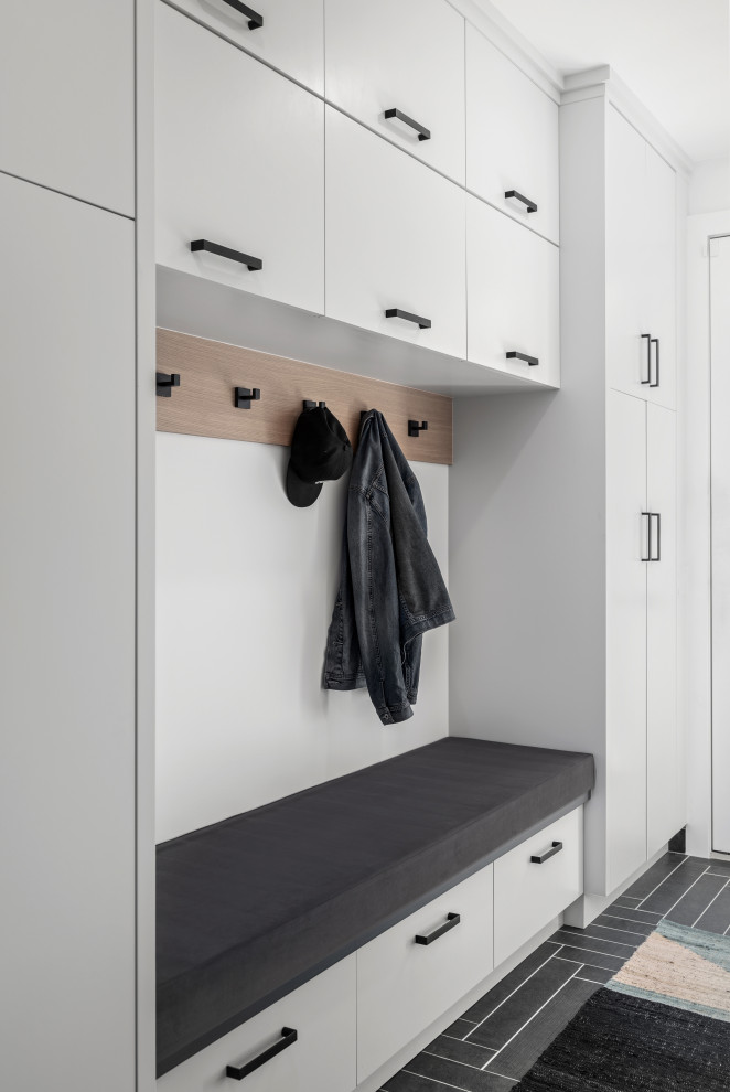 This is an example of a mid-sized modern mudroom in Calgary with a white front door, white walls, porcelain floors, a single front door and black floor.