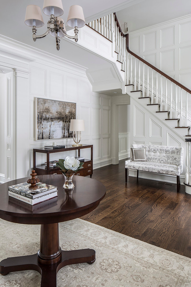 Large transitional foyer in New York with white walls, dark hardwood floors and brown floor.