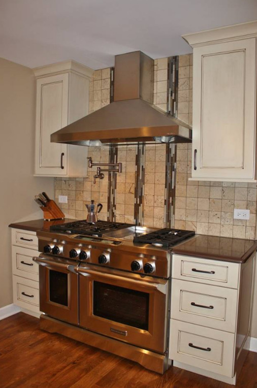 Eat-in kitchen - transitional medium tone wood floor eat-in kitchen idea in Chicago with recessed-panel cabinets, white cabinets, quartz countertops, beige backsplash, stone tile backsplash, stainless steel appliances and an island