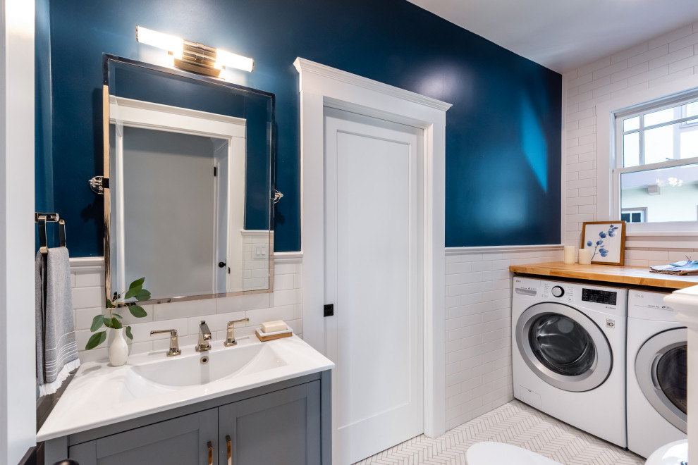 This is an example of a small contemporary bathroom in San Francisco with a two-piece toilet, blue walls, marble flooring, white floors and a laundry area.