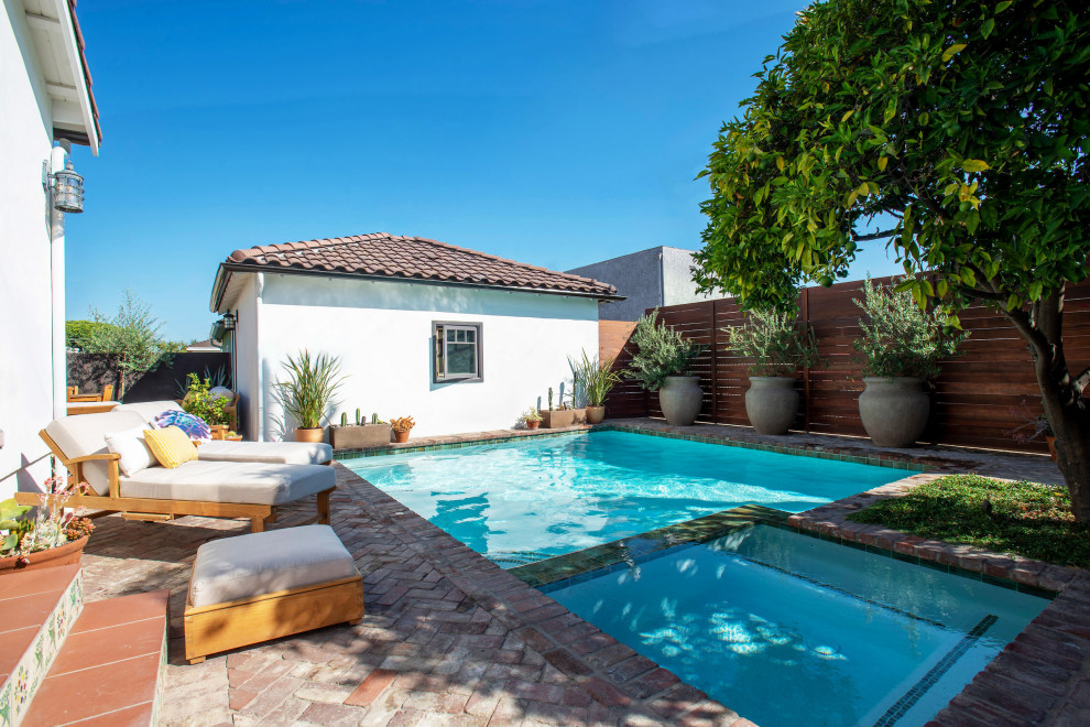 This is an example of a small backyard pool in Los Angeles with brick pavers.