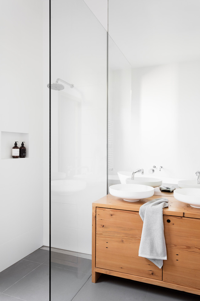 Design ideas for a small contemporary master bathroom in Melbourne with furniture-like cabinets, light wood cabinets, a freestanding tub, an open shower, a one-piece toilet, white tile, porcelain tile, white walls, porcelain floors, a console sink and wood benchtops.