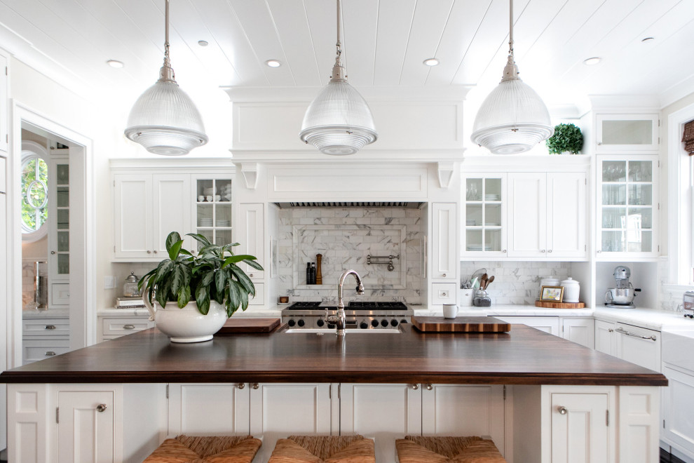 This is an example of a large traditional l-shaped kitchen in San Francisco with a farmhouse sink, shaker cabinets, white cabinets, wood benchtops, grey splashback, with island and brown benchtop.