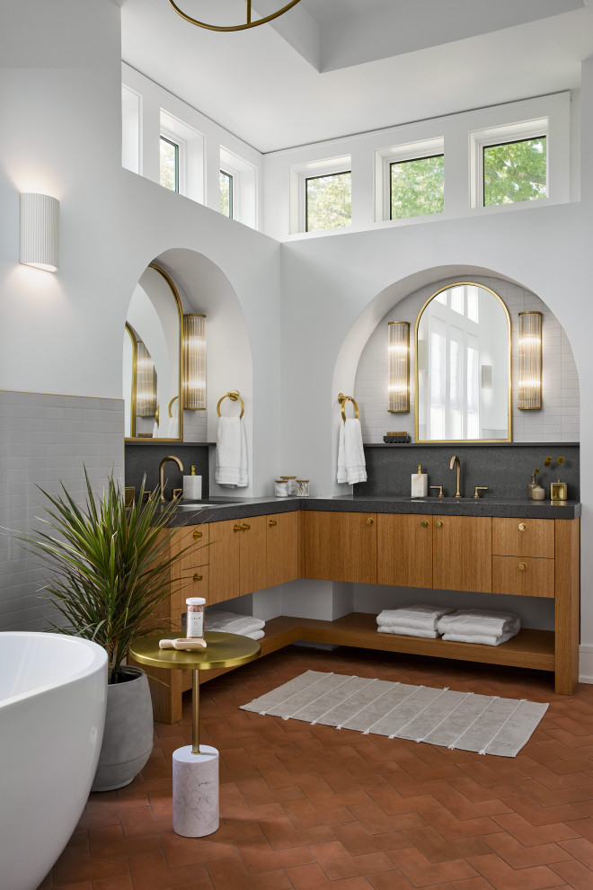Пример оригинального дизайна: ванная комната в современном стиле с плоскими фасадами, фасадами цвета дерева среднего тона, отдельно стоящей ванной, серой плиткой, белыми стенами, полом из терракотовой плитки, врезной раковиной, красным полом, серой столешницей, тумбой под две раковины и встроенной тумбой