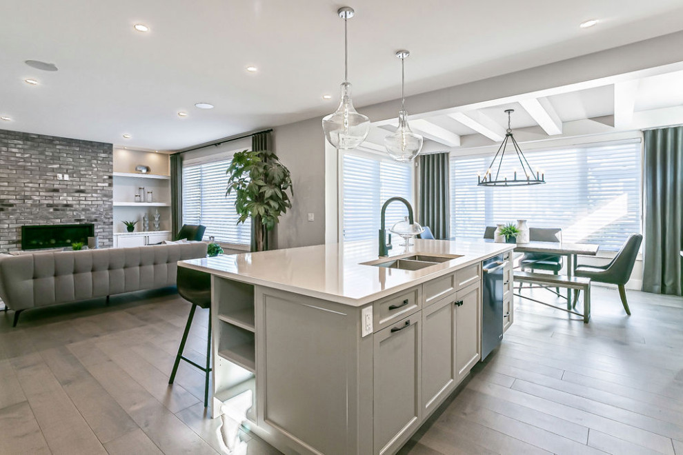 Example of a transitional l-shaped light wood floor and gray floor eat-in kitchen design in Calgary with a double-bowl sink, shaker cabinets, gray cabinets, quartz countertops, stainless steel appliances, an island and white countertops