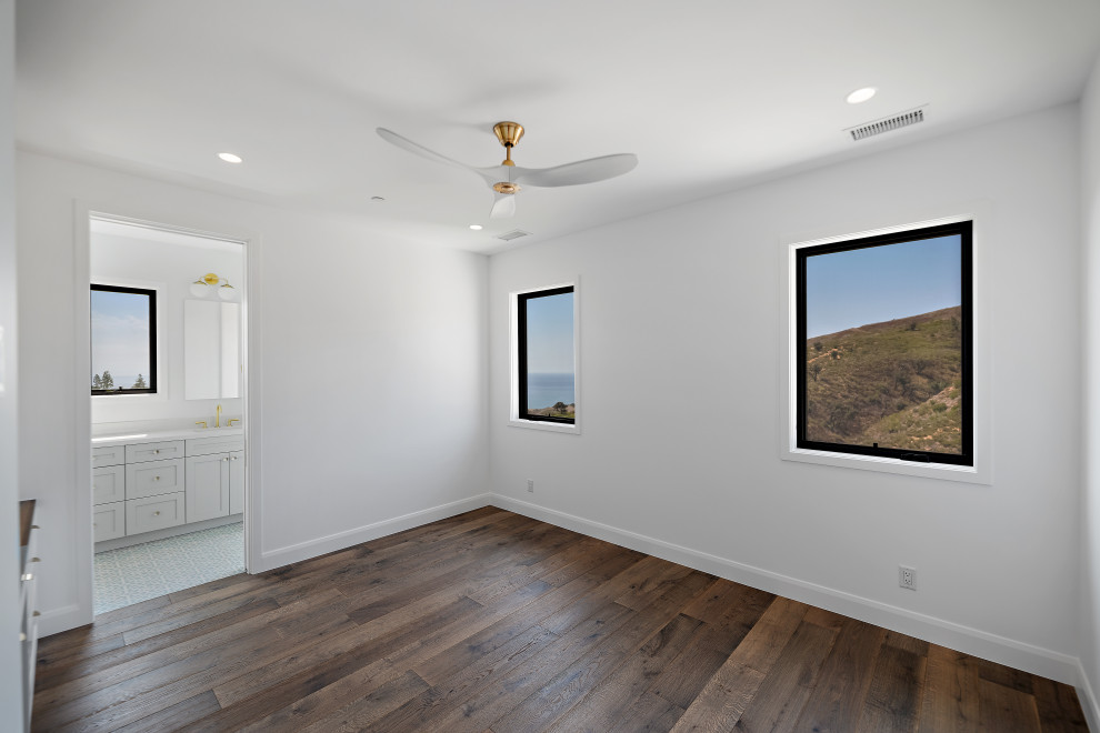 Geräumiges Landhausstil Schlafzimmer mit weißer Wandfarbe, braunem Holzboden und braunem Boden in Los Angeles