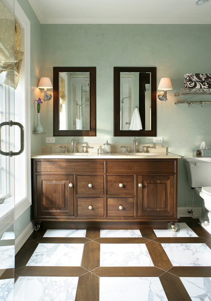 Inspiration for a mid-sized traditional master bathroom in New York with dark wood cabinets, a two-piece toilet, white tile, stone tile, green walls, marble floors, an undermount sink, limestone benchtops, raised-panel cabinets, an alcove shower, white floor and a hinged shower door.