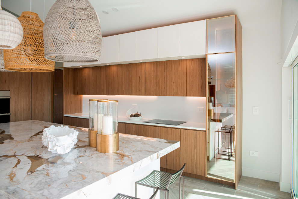 Photo of a mid-sized modern l-shaped open plan kitchen in Miami with an undermount sink, flat-panel cabinets, medium wood cabinets, marble benchtops, white splashback, marble splashback, panelled appliances, ceramic floors, with island, brown floor and beige benchtop.