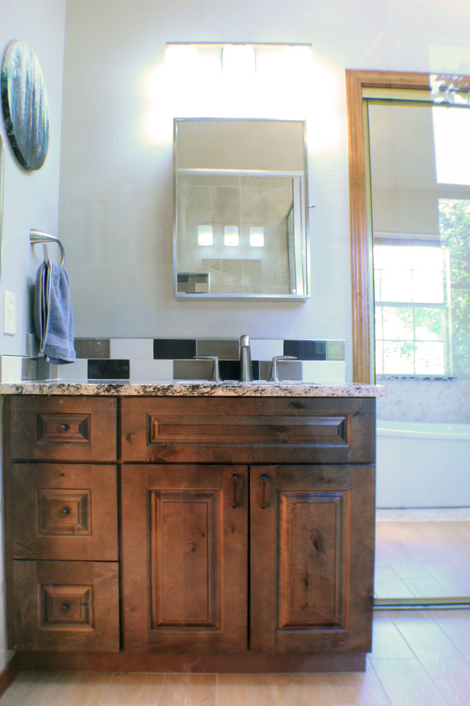 Inspiration for a mid-sized transitional master bathroom in Albuquerque with raised-panel cabinets, medium wood cabinets, a freestanding tub, a corner shower, a one-piece toilet, multi-coloured tile, porcelain tile, porcelain floors, an undermount sink, granite benchtops, beige floor, a hinged shower door and multi-coloured benchtops.