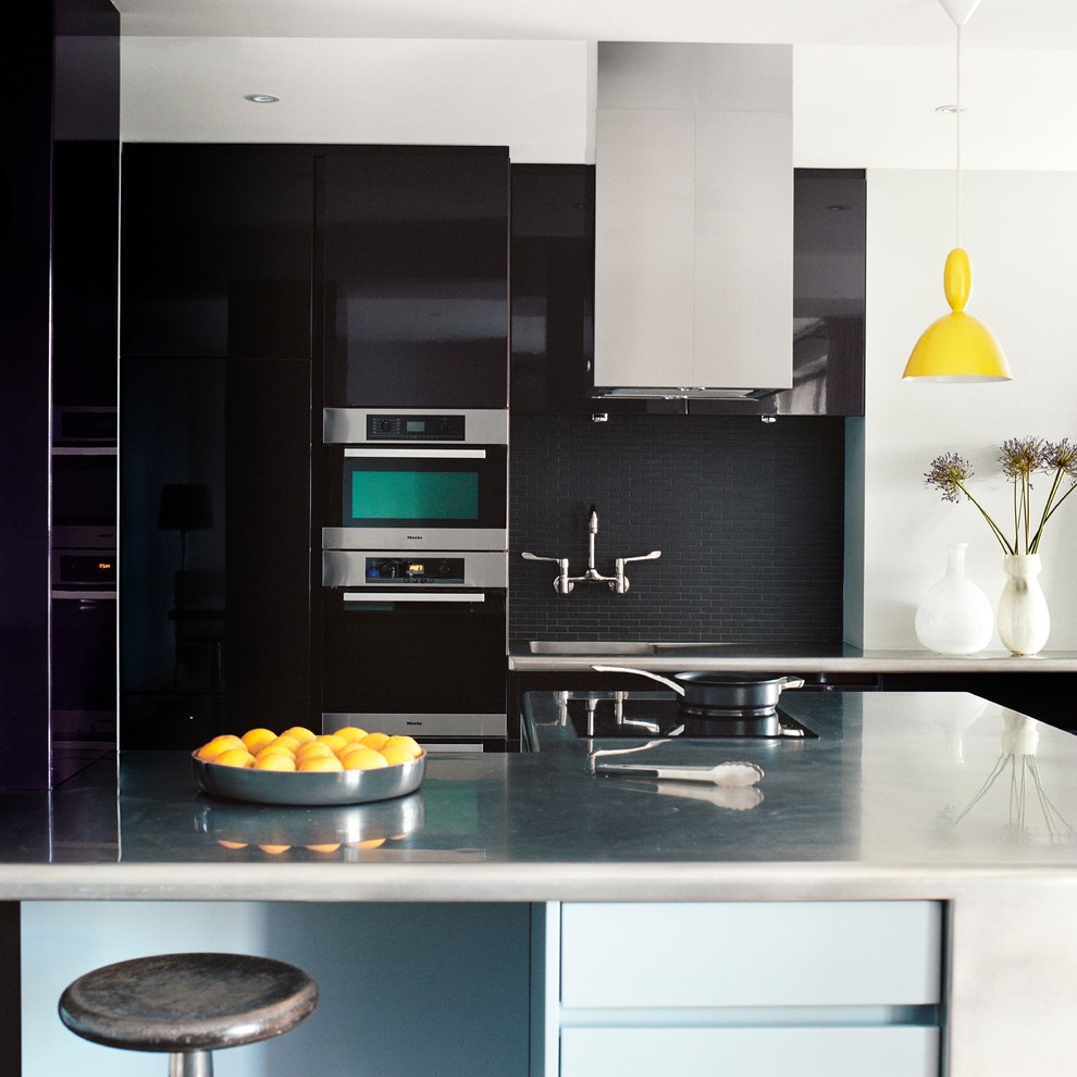 Design ideas for a large contemporary galley eat-in kitchen in London with an integrated sink, flat-panel cabinets, black cabinets, black splashback, subway tile splashback, stainless steel appliances and with island.