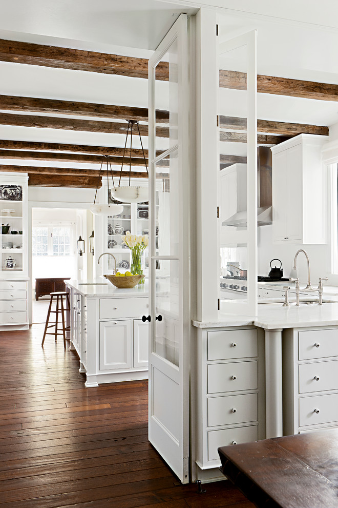 This is an example of a country kitchen in Other with white cabinets, white splashback and beaded inset cabinets.
