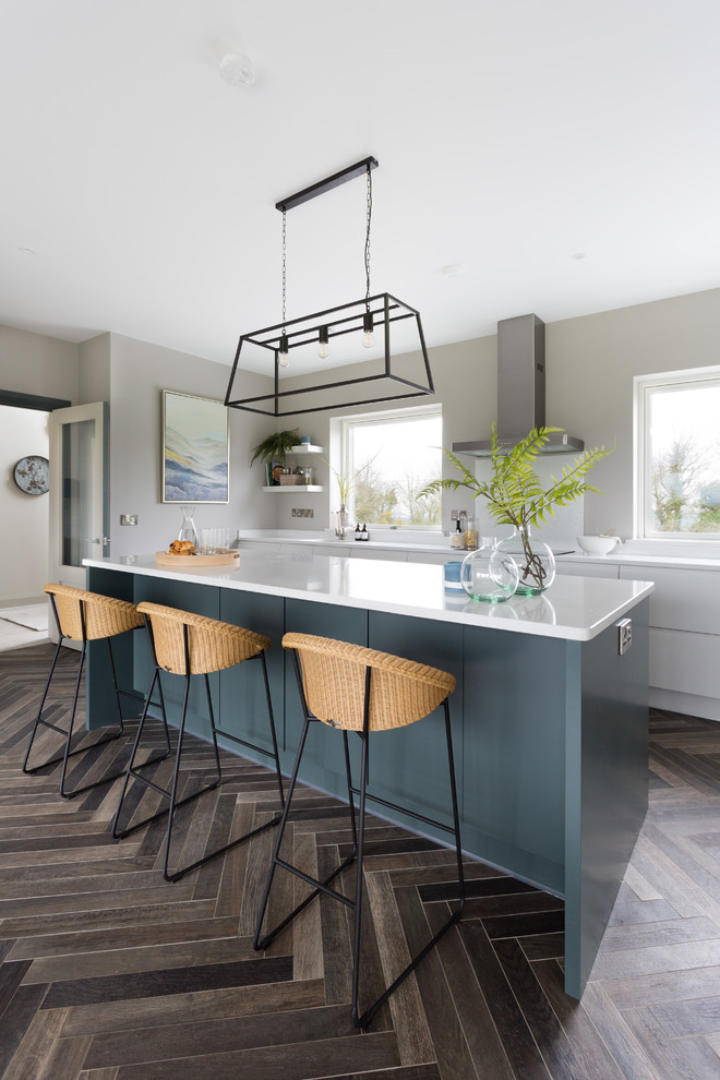 This is an example of a large contemporary l-shaped eat-in kitchen in Cork with an undermount sink, flat-panel cabinets, grey cabinets, quartzite benchtops, white splashback, glass sheet splashback, stainless steel appliances, ceramic floors, with island, brown floor and white benchtop.