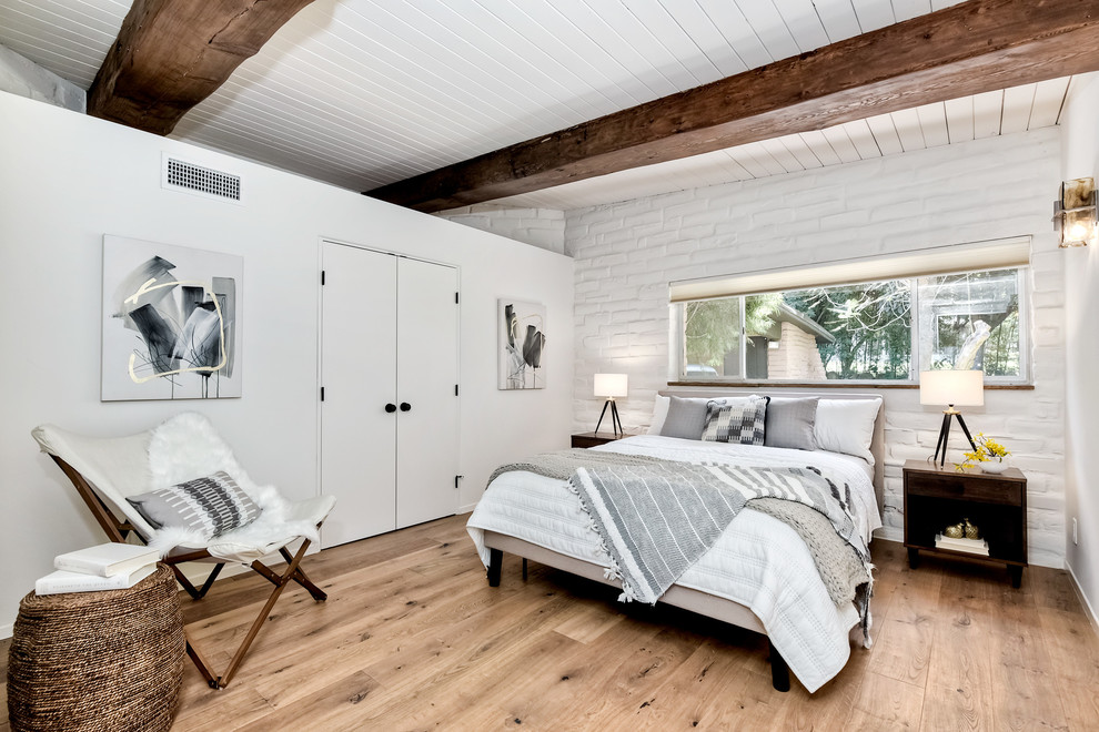 Large midcentury master bedroom in San Diego with white walls, light hardwood floors and brown floor.