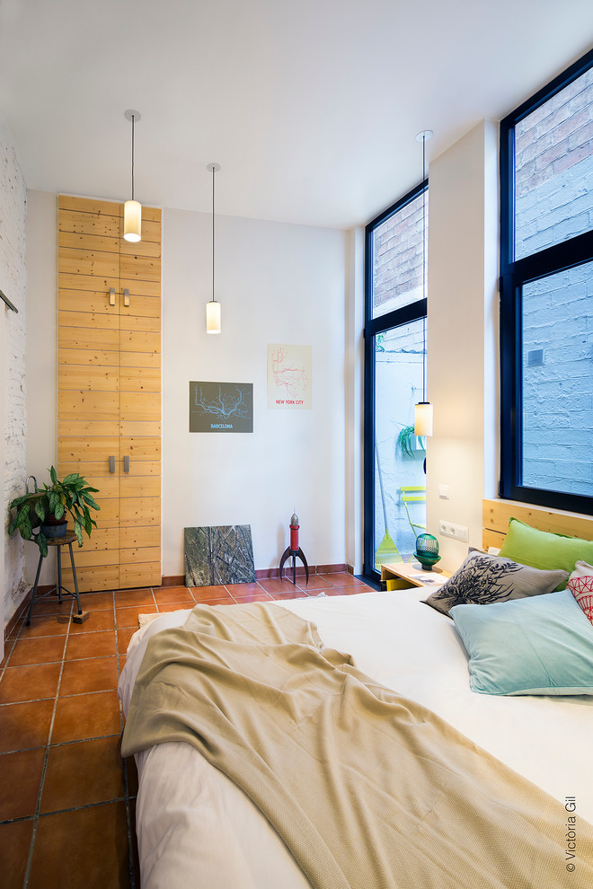 Small modern loft-style bedroom in Barcelona with white walls, terra-cotta floors and no fireplace.