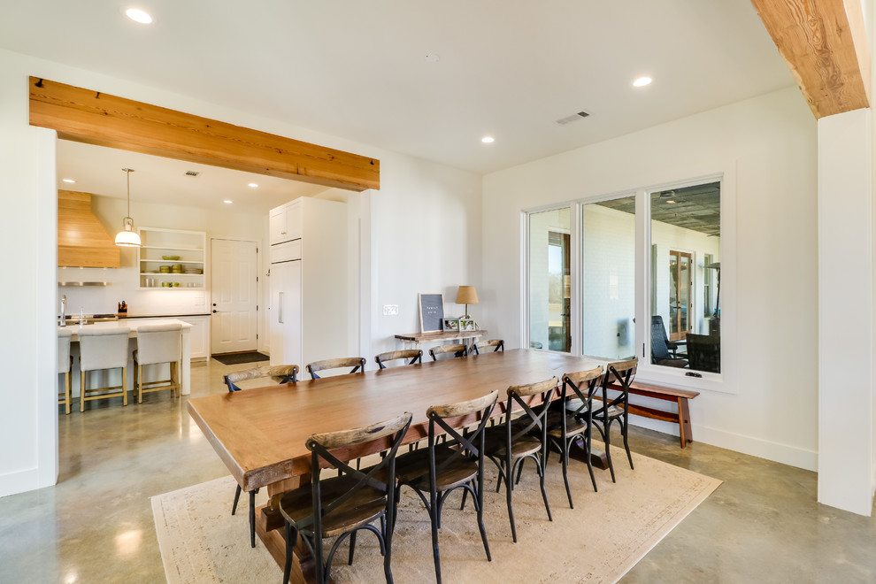 Photo of a large country open plan dining in Jackson with white walls, concrete floors, a standard fireplace, a brick fireplace surround and grey floor.