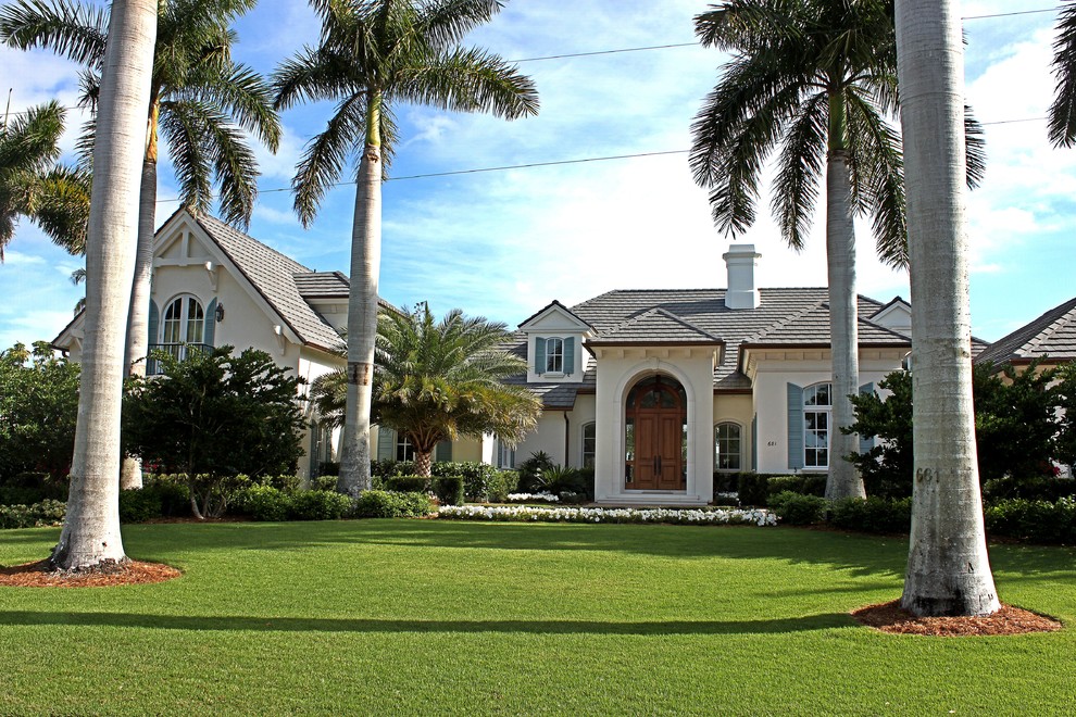 Inspiration for a mid-sized tropical two-storey stucco beige house exterior in Charleston with a hip roof and a tile roof.