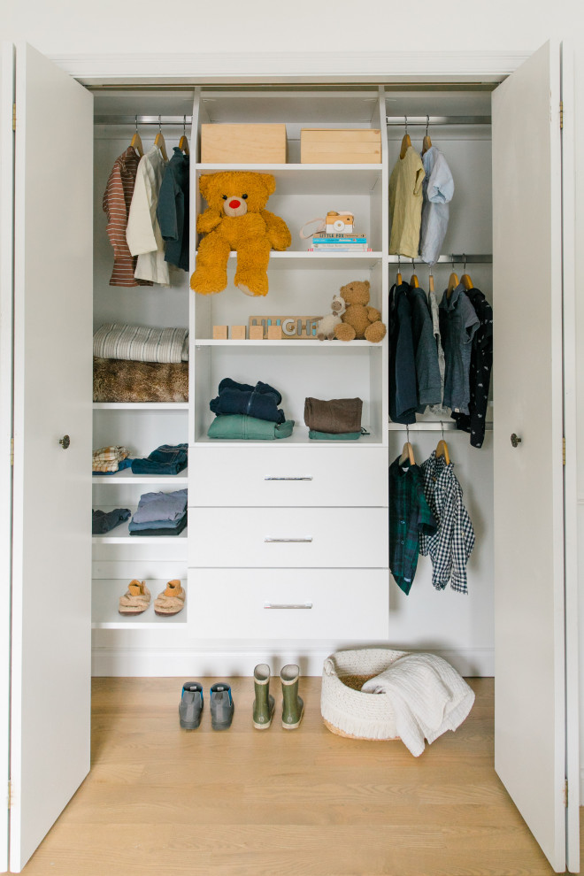 Ejemplo de armario clásico renovado de tamaño medio con armarios con paneles lisos, puertas de armario blancas y suelo de madera clara