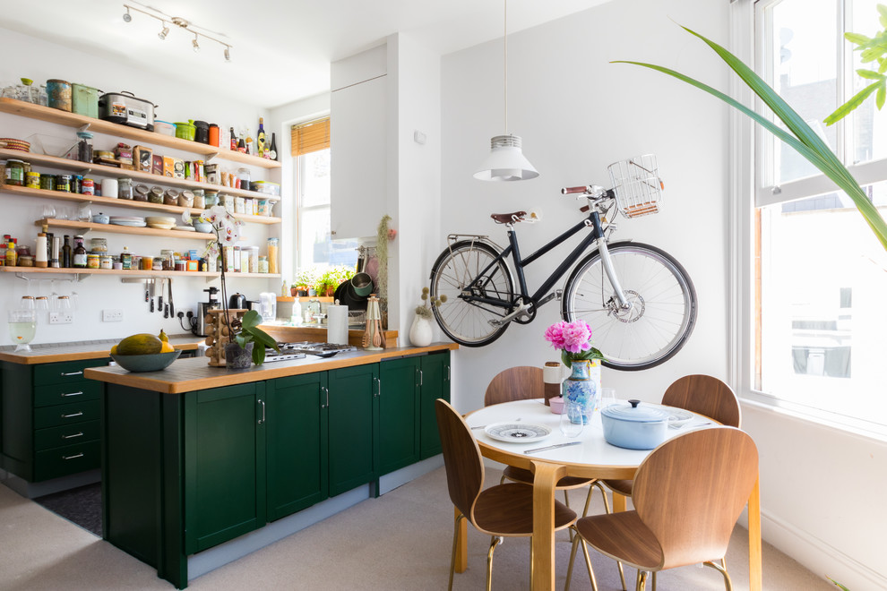 Inspiration for a small scandinavian u-shaped eat-in kitchen in London with shaker cabinets, green cabinets, wood benchtops, a peninsula and beige floor.