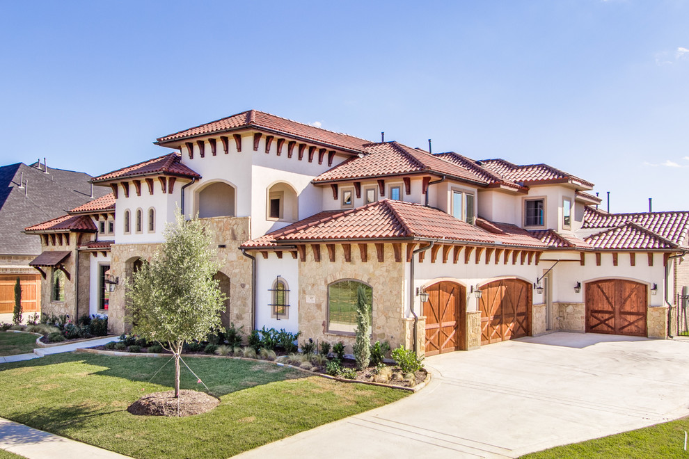 This is an example of an expansive mediterranean two-storey white house exterior in Dallas with mixed siding, a hip roof and a tile roof.