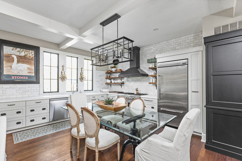 This is an example of a country eat-in kitchen in Indianapolis with shaker cabinets, grey cabinets, multi-coloured splashback, subway tile splashback, stainless steel appliances, dark hardwood floors, brown floor and white benchtop.