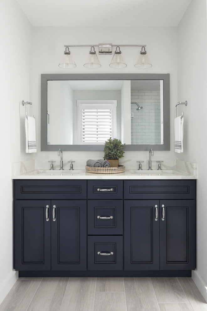 This is an example of a mid-sized transitional 3/4 bathroom in Other with recessed-panel cabinets, black cabinets, white walls, light hardwood floors, an undermount sink, grey floor and grey benchtops.