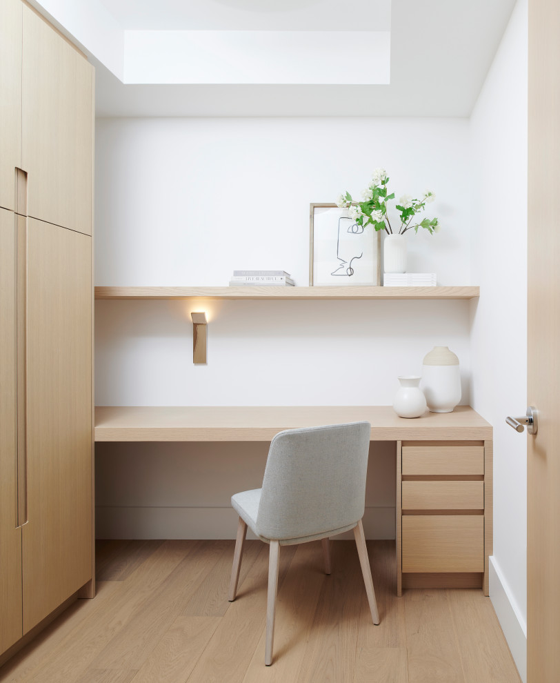 Inspiration for a small modern home office in Toronto with white walls, light hardwood flooring and a built-in desk.