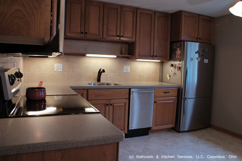 Mid-sized transitional l-shaped ceramic tile eat-in kitchen photo in Columbus with an undermount sink, solid surface countertops, beige backsplash, ceramic backsplash, stainless steel appliances, gray walls, no island, raised-panel cabinets and light wood cabinets