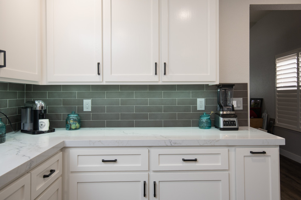 This is an example of a modern kitchen/diner in Sacramento with white cabinets, engineered stone countertops, green splashback, ceramic splashback, stainless steel appliances, a breakfast bar and white worktops.
