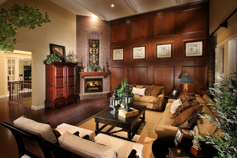 This is an example of a traditional living room in Denver with beige walls, medium hardwood floors, a corner fireplace, a brick fireplace surround and no tv.