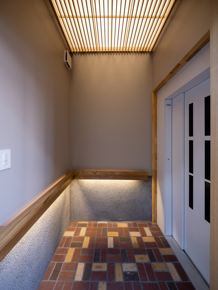 Esempio di un piccolo corridoio contemporaneo con pareti grigie, pavimento in mattoni, una porta scorrevole, una porta grigia, pavimento marrone, soffitto a cassettoni e pareti in perlinato