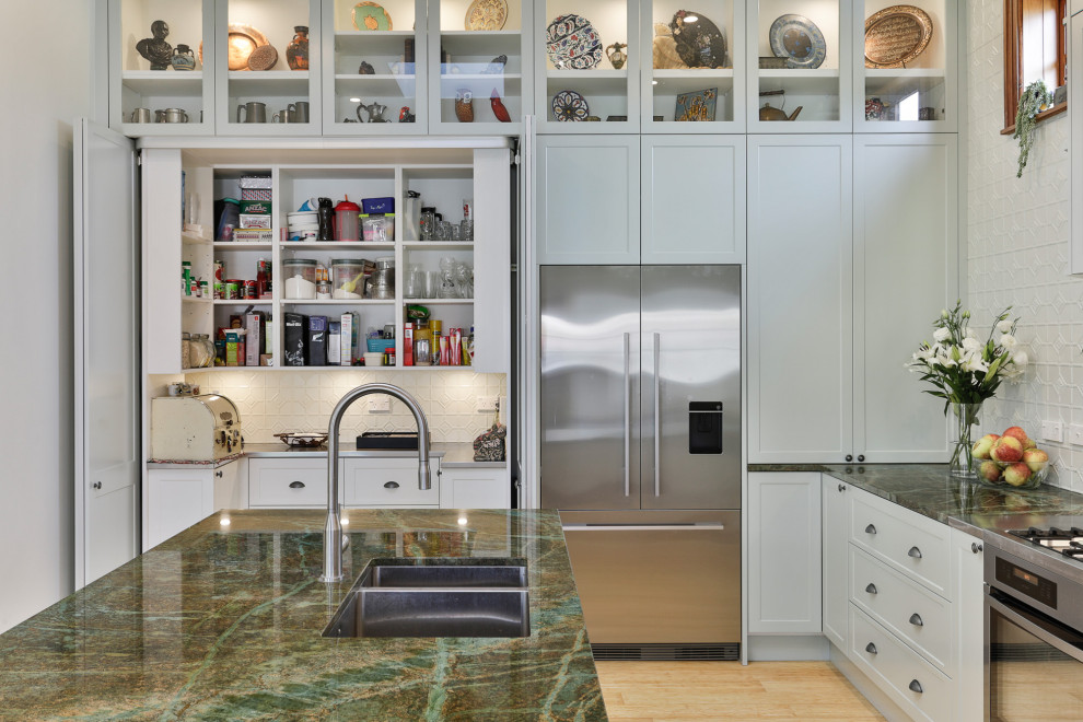 Large traditional l-shaped kitchen pantry in Christchurch with an undermount sink, shaker cabinets, green cabinets, granite benchtops, green splashback, metal splashback, stainless steel appliances, bamboo floors, with island and green benchtop.