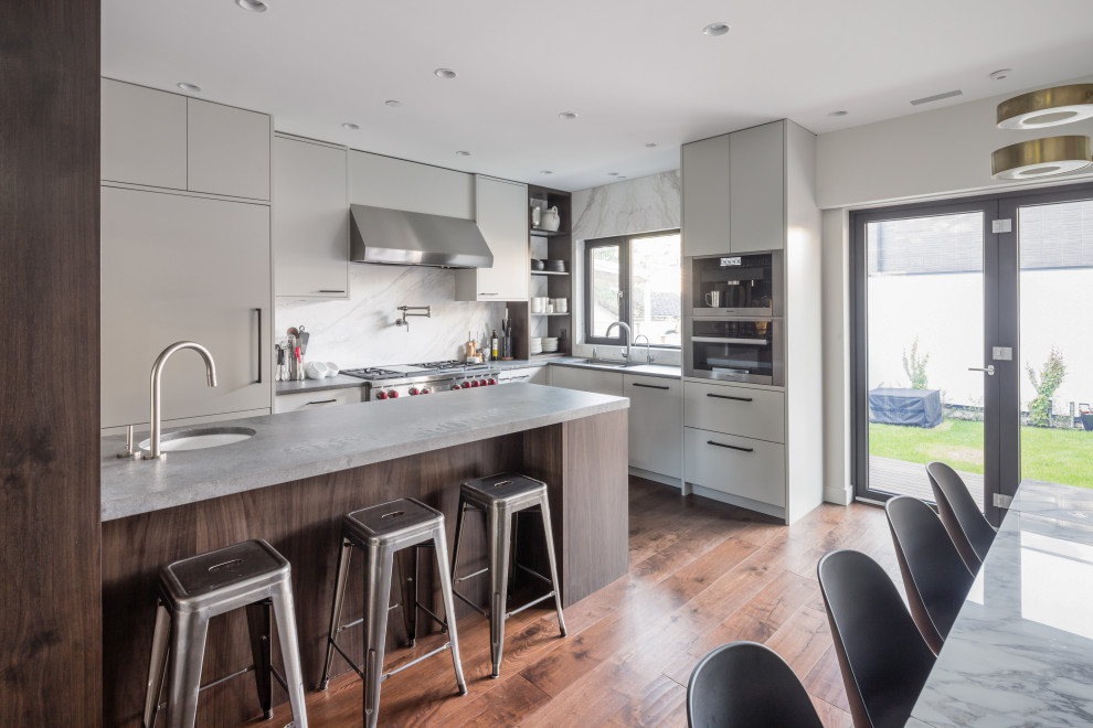 This is an example of a small l-shaped eat-in kitchen in Vancouver with a drop-in sink, beige cabinets, marble splashback, white appliances, dark hardwood floors, with island and brown floor.