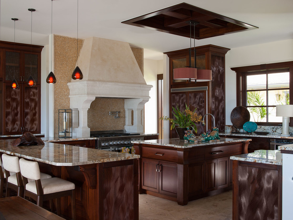 Tropical kitchen in Hawaii with with island, an undermount sink, recessed-panel cabinets, dark wood cabinets, granite benchtops, stainless steel appliances and porcelain floors.