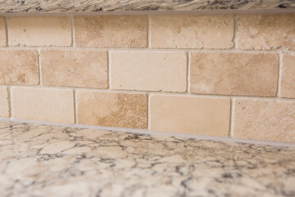 Eat-in kitchen - mid-sized transitional l-shaped medium tone wood floor eat-in kitchen idea in Austin with an undermount sink, recessed-panel cabinets, white cabinets, granite countertops, beige backsplash, stone tile backsplash, stainless steel appliances and an island