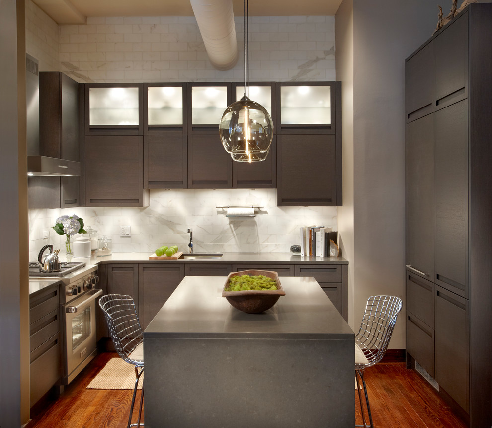 This is an example of a small modern u-shaped eat-in kitchen in Chicago with flat-panel cabinets, white splashback, an undermount sink, grey cabinets, porcelain splashback, panelled appliances, medium hardwood floors and with island.