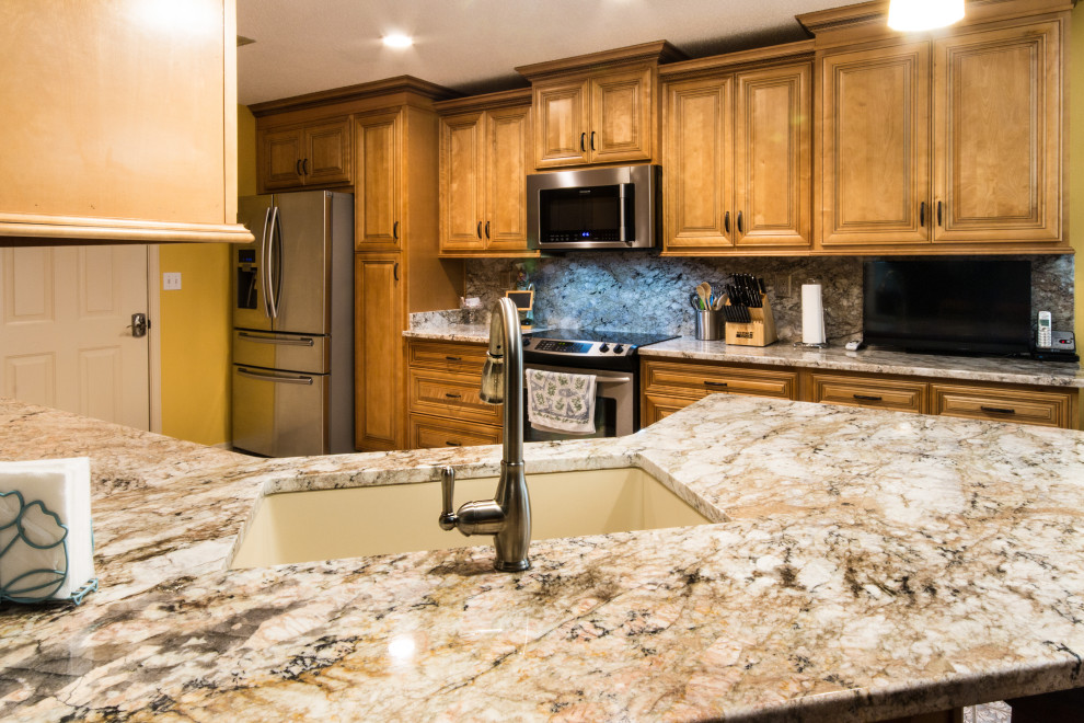 Large u-shaped eat-in kitchen photo with an undermount sink, raised-panel cabinets, medium tone wood cabinets, granite countertops, granite backsplash, stainless steel appliances and a peninsula