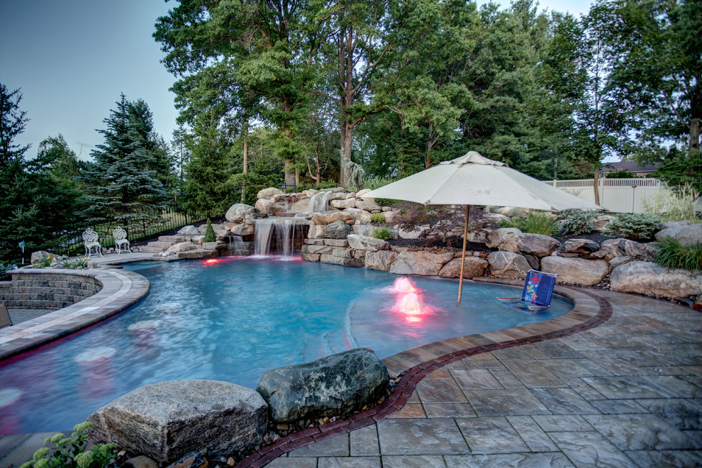Design ideas for a large backyard custom-shaped natural pool in New York with a water feature and natural stone pavers.