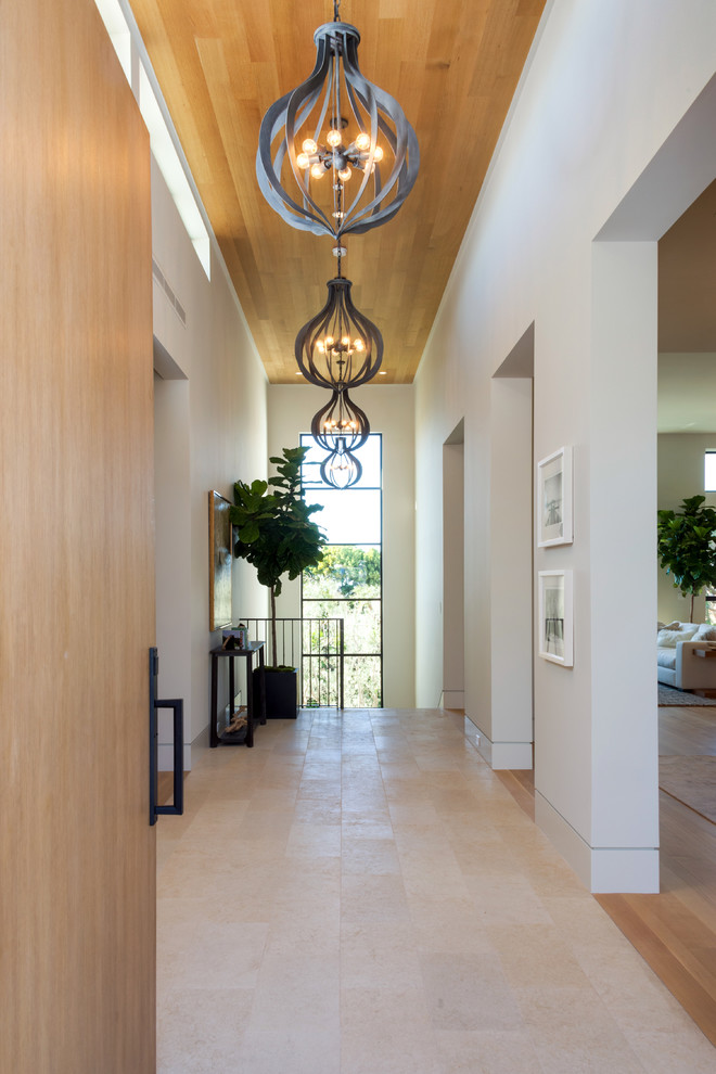 Inspiration for a large contemporary front door in Los Angeles with white walls, concrete floors, a pivot front door and a light wood front door.