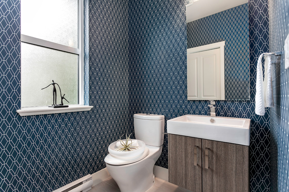 Example of a small trendy porcelain tile powder room design in Vancouver with an integrated sink, flat-panel cabinets, a two-piece toilet, blue walls and dark wood cabinets