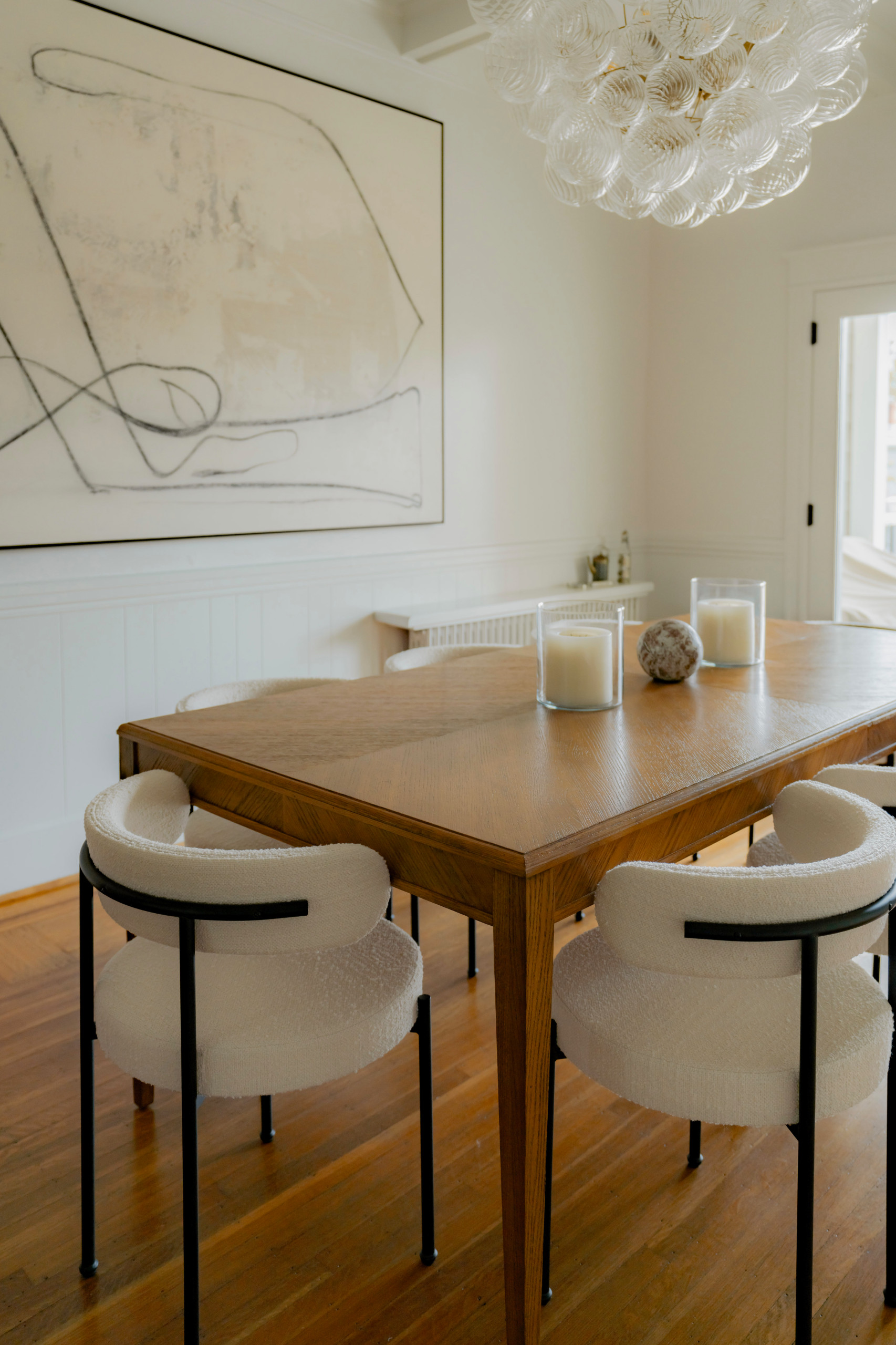 This inviting living room features a harmonious blend of modern elegance and timeless comfort. At the heart of the space, a minimalist beige sofa is paired with two cream lounge chairs, creating a coz