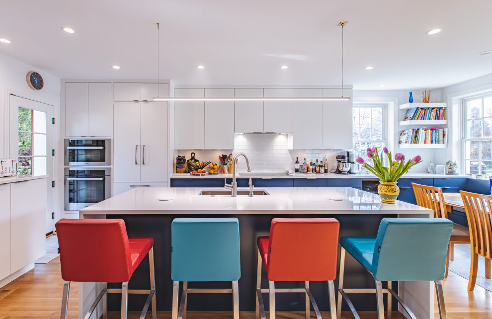 Example of a large trendy u-shaped light wood floor and brown floor open concept kitchen design in DC Metro with an undermount sink, flat-panel cabinets, white cabinets, quartz countertops, white backsplash, subway tile backsplash, stainless steel appliances, an island and white countertops