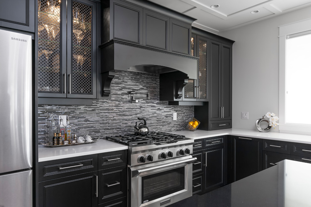 Example of a large transitional u-shaped medium tone wood floor and brown floor kitchen pantry design with an undermount sink, recessed-panel cabinets, black cabinets, quartz countertops, gray backsplash, glass tile backsplash, stainless steel appliances, an island and white countertops