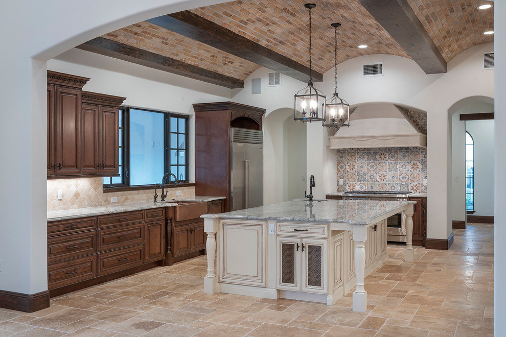 Inspiration for a large mediterranean kitchen in Orlando with a farmhouse sink, raised-panel cabinets, dark wood cabinets, granite benchtops, ceramic splashback, stainless steel appliances, travertine floors, with island, beige floor and grey benchtop.